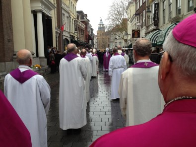 bisschoppen en priesters doen mgr. Muskens uitgeleide na de uitvaart