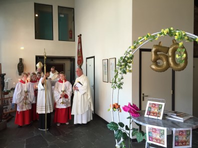 misdienaars en priesters opgesteld voor de Mis, rchts de kraam met het nieuwe parochieboek