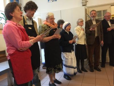 Vrijwilligers en zusters zingen een lied voor de gasten aan de maaltijd voor de daklozen