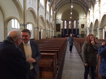 De kerk van binnen; diaken Hans Bruin is in gesprek met een parochiaan